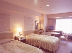 Habitación de hotel con 2 camas, escritorio y TV. en Tosagyoen, en Kochi