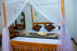 迪克韋勒的住宿－Thusitha s nest，一间卧室配有带蚊帐的天蓬床。
