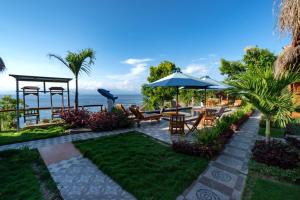 a garden with tables and chairs and the ocean in the background at Sundi Ocean Bungalow by ABM in Nusa Penida