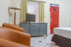 a living room with a tv and a couch and a red door at RedDoorz Plus @ Otista Garut in Garut +26 photos