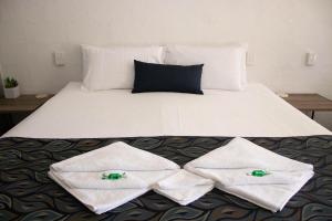 
a white bed with white pillows and pillows on top of it at Bundaberg Spanish Motor Inn in Bundaberg
