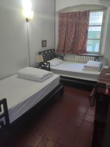 two beds in a room with a window at Qianmen Hostel (Beijing Tian'anmen Dashilan) in Beijing