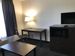 a hotel room with a desk with a television and a lamp at Days Inn & Suites by Wyndham Gresham in Gresham
