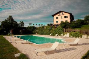 une piscine avec des chaises longues et une maison dans l'établissement Cascina Papa Mora, à Cellarengo