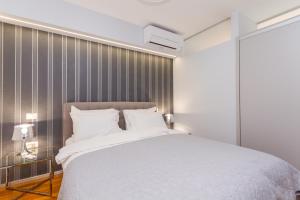 a bedroom with a white bed and a striped wall at Apartments Lux by Locap Group in Portorož