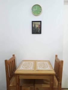 einem Holztisch mit zwei Stühlen und einer Uhr an der Wand in der Unterkunft El Pueblo Manila Condominium in Manila