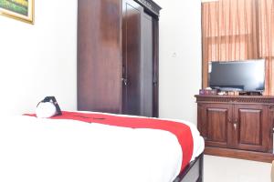 1 dormitorio con 1 cama, TV y armario en RedDoorz Syariah near Gelora Delta Sidoarjo 2, en Sidoarjo