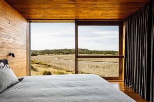 a bedroom with a large window with a view of a field at Seastacks at The Denison in Bicheno