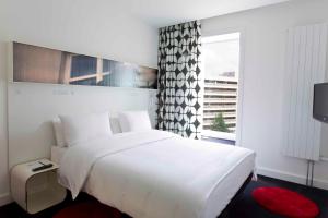 a white bedroom with a large bed and a window at Hotel Gat Point Charlie in Berlin +31 photos