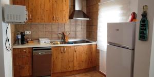 a kitchen with wooden cabinets and a white refrigerator at Can Angel in Sant Francesc Xavier