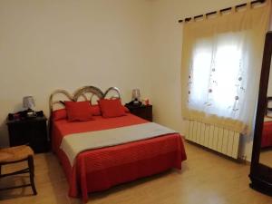 Un dormitorio con una cama con almohadas rojas y una ventana en Casa Simona, en Navas de Estena