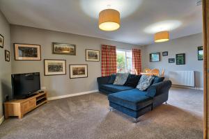 a living room with a blue couch and a tv at Heartseed House Bed & Breakfast in Dornoch