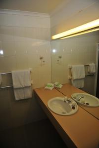 een badkamer met een wastafel, een spiegel en handdoeken bij Mildura Plaza Motor Inn in Mildura