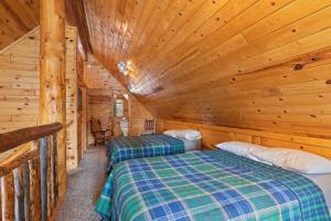 a bedroom with two beds in a log cabin at Trappers Chalet by KABINO Luxury Mountain Lodge Hot Tub Close to Yellowstone and Harriman Park Grill WiFi in Island Park +19 photos