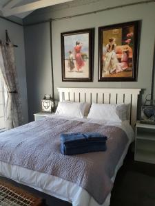 a bedroom with a large bed with two pictures on the wall at At Rest in Zeerust