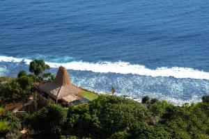 an aerial view of the ocean with a thatch roof at Lelewatu Resort Sumba in Watukarere