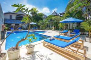 a swimming pool with two lounge chairs and an umbrella at Martas Hotel in Gili Trawangan