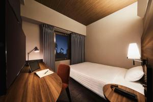 um pequeno quarto de hotel com uma cama e uma secretária em RIHGA PLACE HIGOBASHI em Osaka