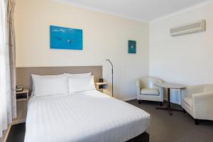Pokój hotelowy z białym łóżkiem i krzesłem w obiekcie Best Western Olde Maritime Motor Inn w mieście Warrnambool