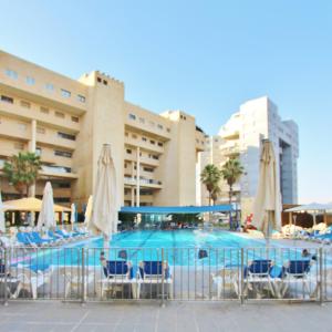une piscine avec des chaises et des parasols en face d'un hôtel dans l'établissement POOL GYM AND BEACH FRONT 3 BEDROOMS LUXURY TEL AVIV APARTMENT, à Tel Aviv