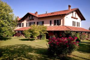 une grande maison avec une cour ornée de fleurs roses dans l'établissement Cascina Papa Mora, à Cellarengo