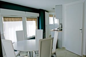 a dining room with a white table and chairs at Résidence Thalacap in Cap d'Agde