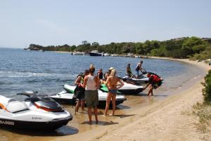 a group of people standing on a beach next to boats at Residence Ribellinu in Pianottoli-Caldarello