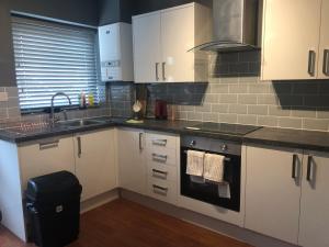 a kitchen with white cabinets and a sink and a stove at Central Unite management Ltd in Manchester