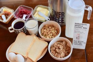a table with eggs toast bread and other breakfast foods at Noboribetsu Guest House AKA & AO in Noboribetsu