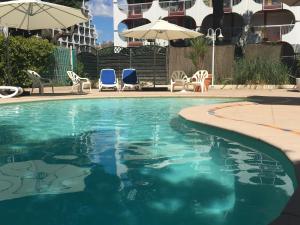 - une piscine avec des chaises et des parasols à côté d'un bâtiment dans l'établissement Hôtel Les Rives Bleues, à La Grande Motte