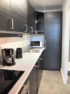 uma cozinha com armários pretos e um balcão branco em Studio tout équipé - 300m gare - 005 em Rouen