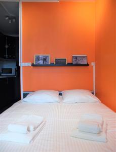 um quarto com uma parede laranja e uma cama com duas toalhas em Studio tout équipé - 300m gare - 005 em Rouen