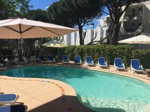 una piscina con sedie e ombrelloni di Hôtel Les Rives Bleues a La Grande-Motte