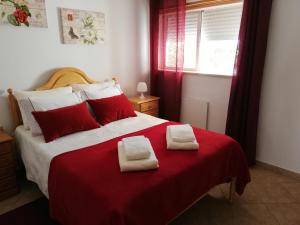 um quarto com uma cama vermelha e branca com toalhas em Amoreira Alvor - Praia e Piscina em Alvor