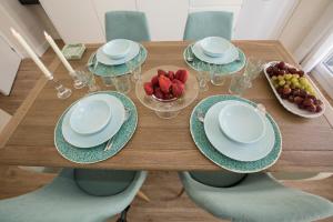 a wooden table with plates and bowls of fruit on it at Gr Suites Boutique Catedral in Málaga