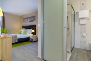 a bedroom with a bed and a bathroom with a shower at Hotel Pinija in Petrcane