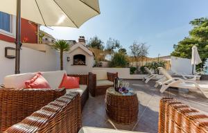 a patio with wicker chairs and tables and an umbrella at Holiday Villa Nostra in Trogir