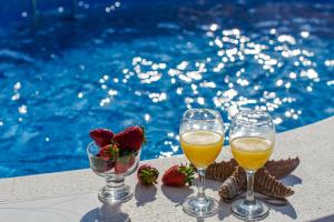 Holiday Villa Nostra في تروغير: كأسين من النبيذ والفراولة على طاولة بجوار حمام السباحة