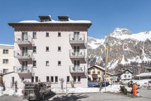 a large white building in front of a mountain at Hotel Post Sils Maria in Sils Maria