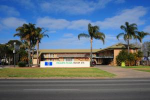 a building with palm trees in front of a street at Mildura Plaza Motor Inn in Mildura