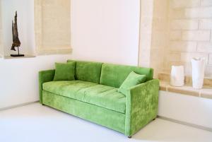 - un canapé vert dans une chambre dotée d'un mur blanc dans l'établissement B & B Sotto la Volta, à Massafra