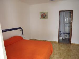 a bedroom with a bed with an orange blanket and a shower at Residencia Laranjeira in Odeceixe