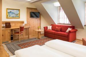 salon z czerwoną kanapą i biurkiem w obiekcie Hotel-Restaurant Kirchenwirt w mieście Weissenkirchen in der Wachau