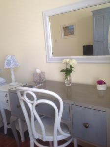 a desk with a white chair and a vase of flowers at The Old Post House B&B in St Just