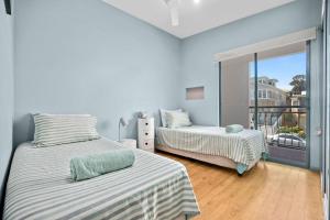 a bedroom with two beds and a balcony at Nosie 1 in Sawtell