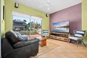 a living room with a couch and a flat screen tv at Nosie 1 in Sawtell