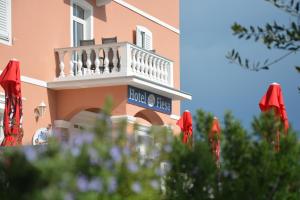 een roze gebouw met een balkon en rode parasols bij Hotel Fiesa in Piran