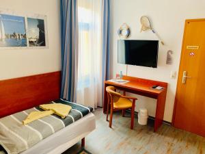 ein Hotelzimmer mit einem Schreibtisch, einem Bett und einem Computer in der Unterkunft Hotel-Pension "Petridamm" in Rostock