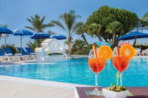 two glasses of orange juice next to a swimming pool at Hotel Capizzo in Ischia