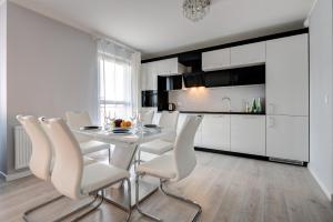 een witte keuken met een tafel en witte stoelen bij Live & Travel Apartments - Waterlane Island in Gdańsk